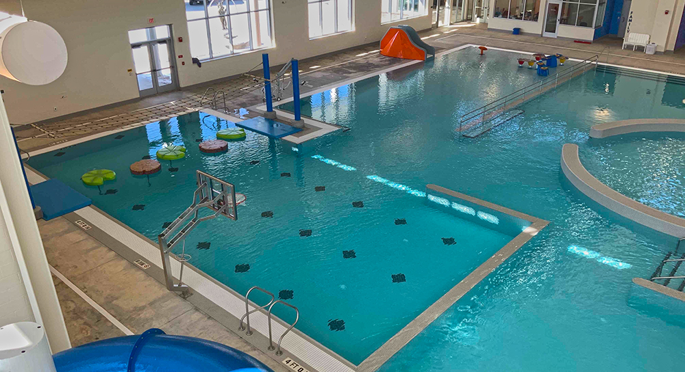 Sheridan YMCA's indoor leisure pool with a Lilly pad crossing, tot slide, and zero depth beach entry